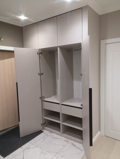 an empty walk in closet with white cupboards and marble flooring on the ground