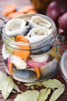 a jar filled with fruit and vegetables on top of a wooden table next to other fruits