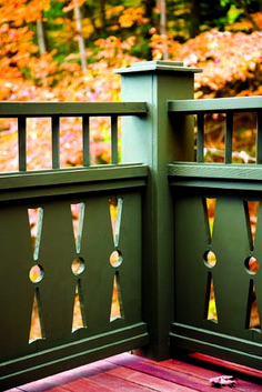 two green gates on a wooden deck in front of some trees with fall foliage behind them