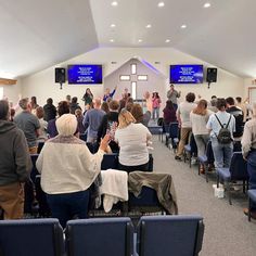 a group of people standing in front of a room filled with blue chairs