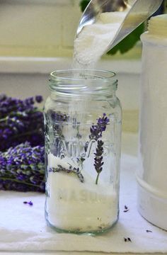 lavender flowers are being poured into a mason jar filled with salt and water to cool off the cold weather