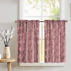 a window with pink curtains next to a vase filled with white flowers and a potted plant