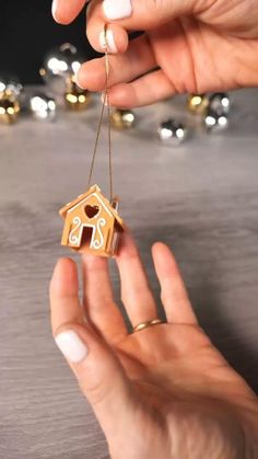 two hands holding a small wooden house ornament