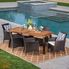 an outdoor dining table and chairs near a pool