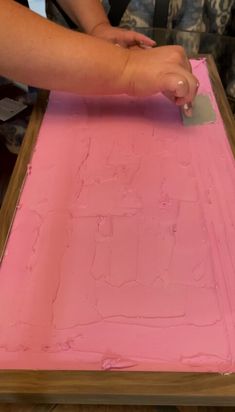 someone is using a knife to cut out the pink paper on top of the table