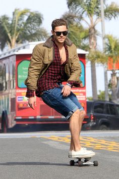 a man riding a skateboard down a street next to a red bus and palm trees