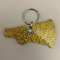 a yellow glitter key chain with the word cheer on it