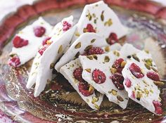 white desserts with raspberries and pistachio on a plate