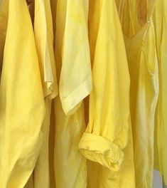 there are many yellow shirts hanging on the rack