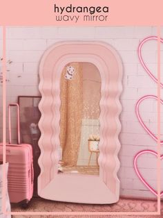 a pink mirror sitting on top of a floor next to suitcases and a wall