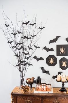 a table with halloween decorations on it and bats hanging from the wall behind it,