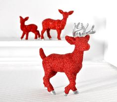 two red glitter deer figurines on white surface