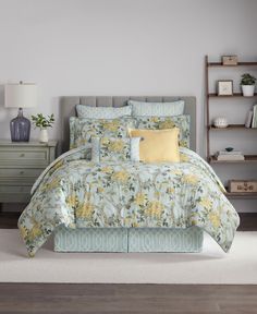 a bed with yellow and blue comforters on top of it in a room next to a dresser