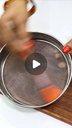 a woman is holding a metal pan on a wooden board with an orange in it