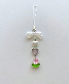 a glass ornament hanging on a white wall with two hearts and a flower