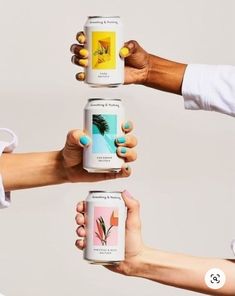 four people holding up cans of drinks in their hands with the same design on them