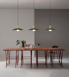 a table with four chairs and three lights hanging from it's sides, in front of a gray wall