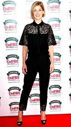 a woman standing on top of a red carpet wearing black pants and lace blouses