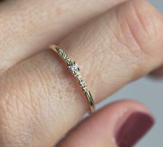 a woman's hand with a diamond ring on top of her finger and the other hand holding it