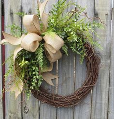 a wreath is hanging on the side of a fence with greenery and burlocks