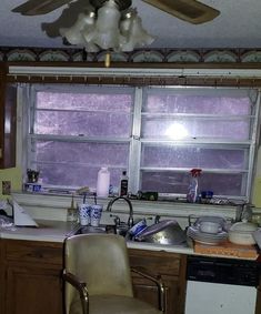 a kitchen with a ceiling fan, sink and stove top oven next to a window