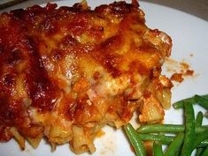 a white plate topped with lasagna and green beans