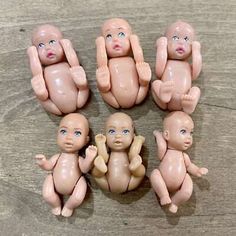 six baby dolls sitting on top of a wooden table