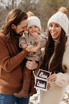 a man and woman holding a baby in the snow