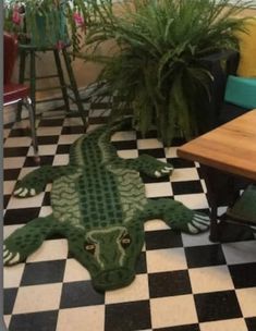 a green alligator rug sitting on top of a black and white checkerboard floor