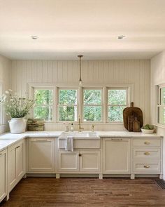 a large kitchen with white cabinets and wood flooring is pictured in this image from the front view