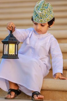 a little boy sitting on the steps holding a lantern