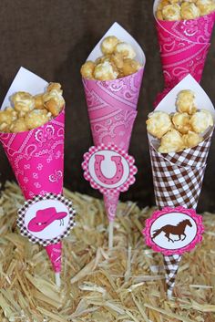 three cones filled with popcorn sitting on top of hay