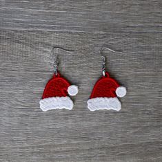 red and white santa hat earrings on wooden background