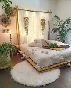 a white bed sitting in a bedroom next to two potted plants on either side of the bed