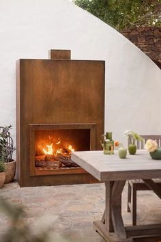 an outdoor fireplace is shown with potted plants on the table and in front of it