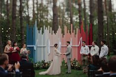 a bride and groom standing in front of a colorful wall at their outdoor wedding ceremony