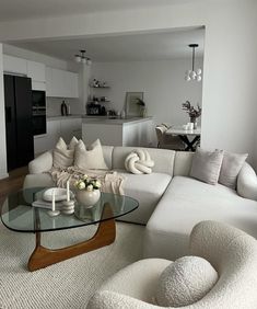 a living room filled with furniture and a glass top table in front of a white couch