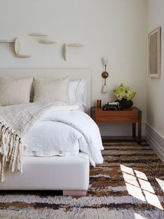 a white bed sitting in a bedroom on top of a rug