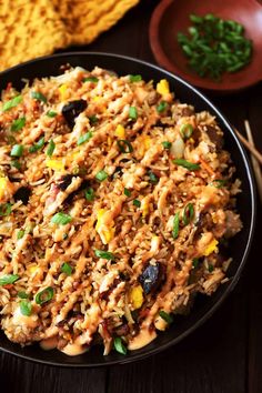 a bowl filled with rice and vegetables on top of a wooden table