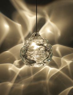 a clear glass light hanging from a black cord in the middle of an abstract background