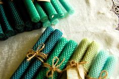 several green and blue rolled up candles on a lace doily