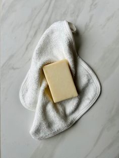 a bar of soap sitting on top of a white towel next to a piece of butter