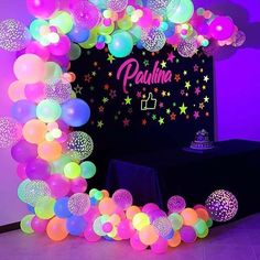 an arch made out of balloons with stars and confetti on the top, in front of a purple wall