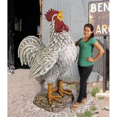 a woman standing next to a statue of a rooster