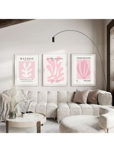 a living room filled with white furniture and pink art on the wall above two couches