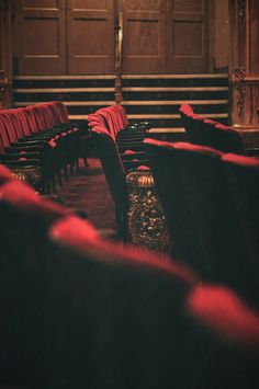 an empty auditorium with rows of chairs and red velvet upholstered seats on the floor