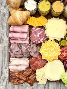 an assortment of cheeses, meats and vegetables on a cutting board