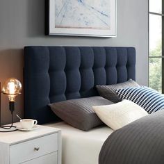 a blue headboard with two pillows on it in a bedroom next to a night stand