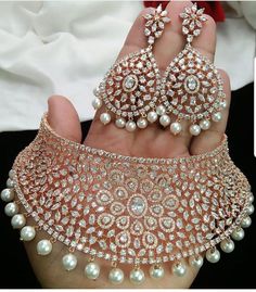 a person holding two pieces of jewelry in their hand and the other piece has pearls on it