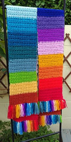 two crocheted towels are hanging on a rack in front of some bushes and trees